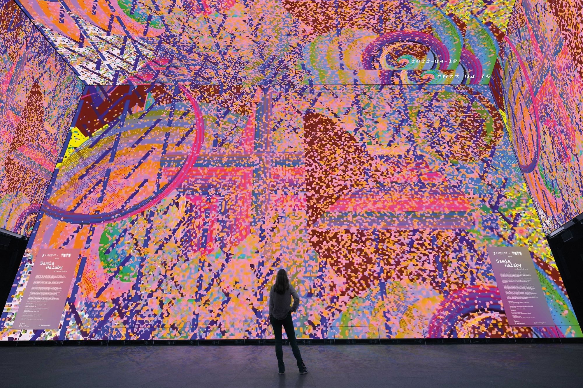 The walls of a room are covered in swirling pink designs as part of an art installation by Samia Halaby