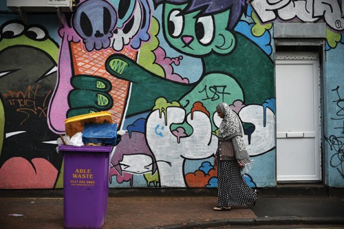 A woman walks past graffiti in the Stokes Croft area of Bristol