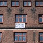 A banner hangs on the side of a building bearing the message: 'Leave no-one behind'