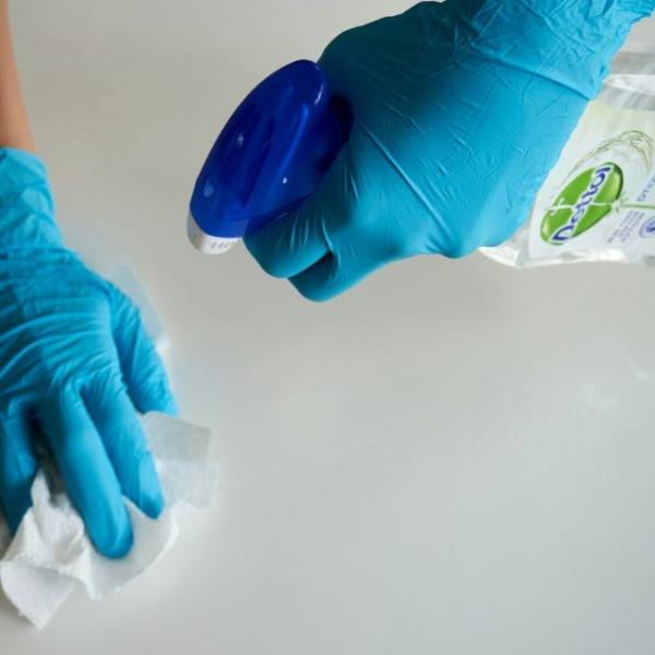 Somebody cleans a surface using antibacterial spray