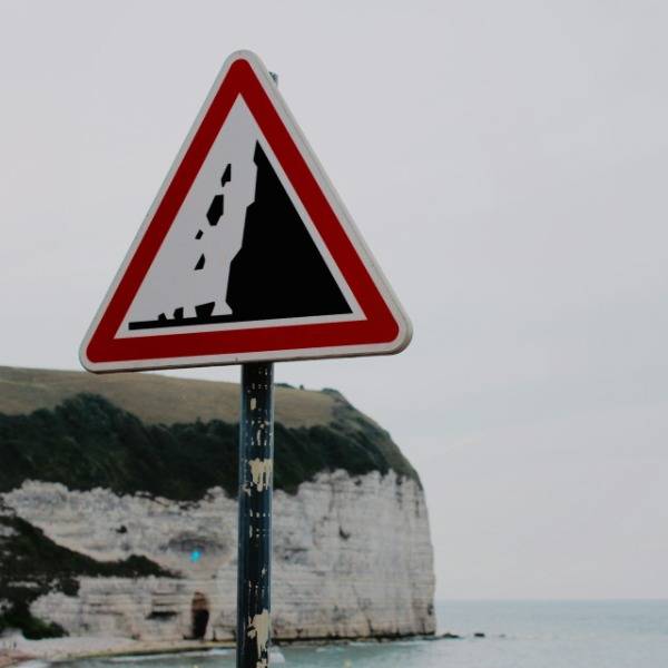 A sign warns of possible rockfall near cliffs in France
