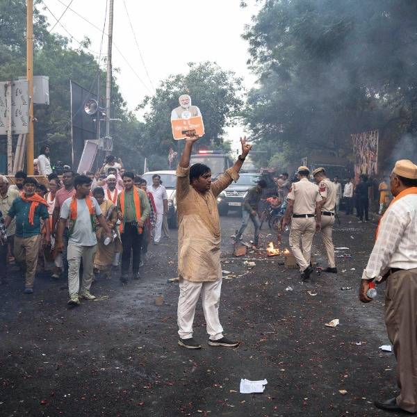 Supporters of Indian Prime Minister Narendra Modi celebrate in the street after he won a third consecutive term in June. In the centre, one man holds up a paper cutout of Modi in one hand while flashing the V for Victory sign with the other hand
