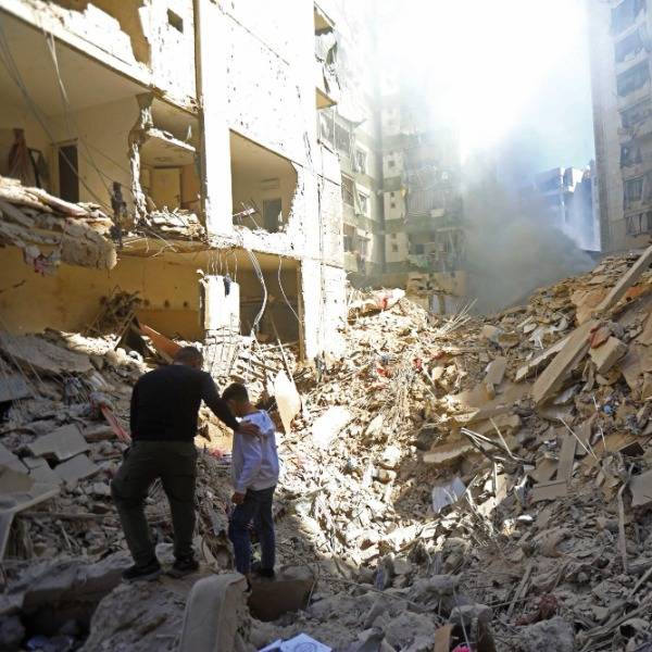 A man comforts a boy as they survey the ruins of an apartment block in Beirut that was destroyed by an Israeli strike