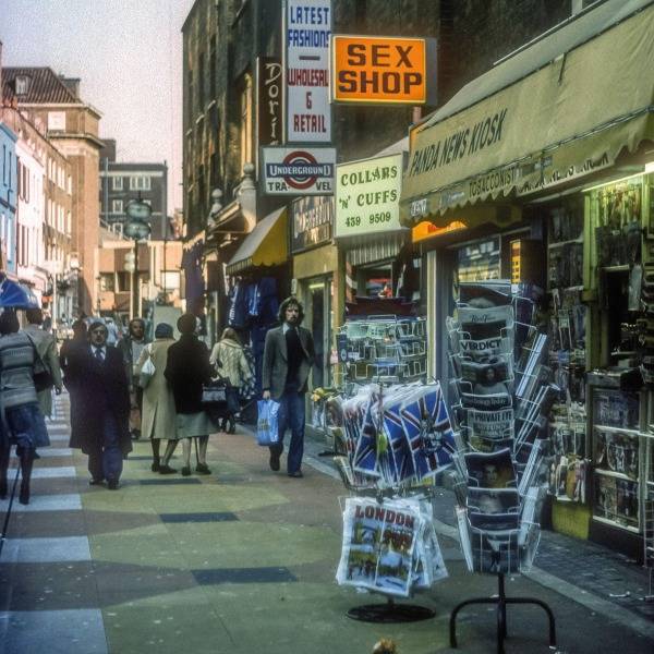 A man strolls past a sign reading 'Sex Shop' in Soho, 1976