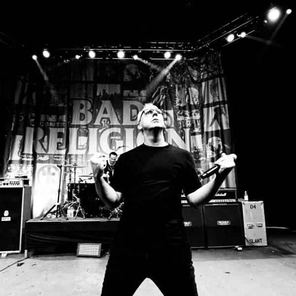 A black and white photo of Greg Graffin on stage with his band Bad Religion