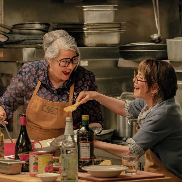 In a scene from 'Nonnas', two characters - Roberta and Teresa - laugh together as they cook