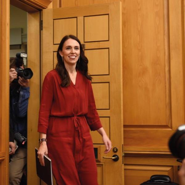 Jacinda Ardern enters a room followed by photographers