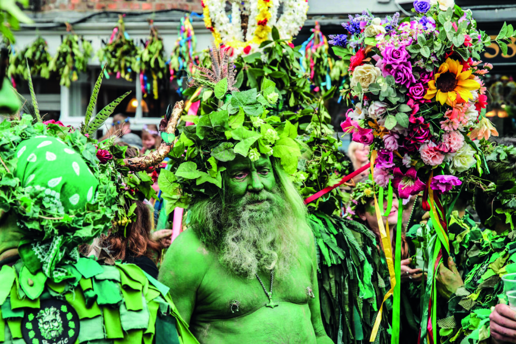 A main painted in green, with his head covered in foliage, takes part in the Jack in the Green parade