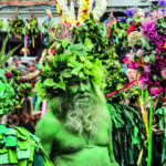 A main painted in green, with his head covered in foliage, takes part in the Jack in the Green parade