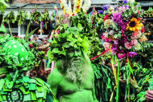 A main painted in green, with his head covered in foliage, takes part in the Jack in the Green parade
