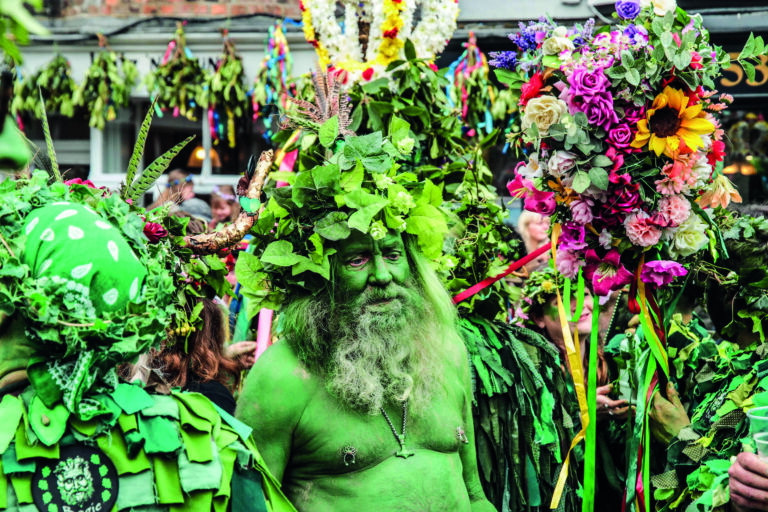 A main painted in green, with his head covered in foliage, takes part in the Jack in the Green parade