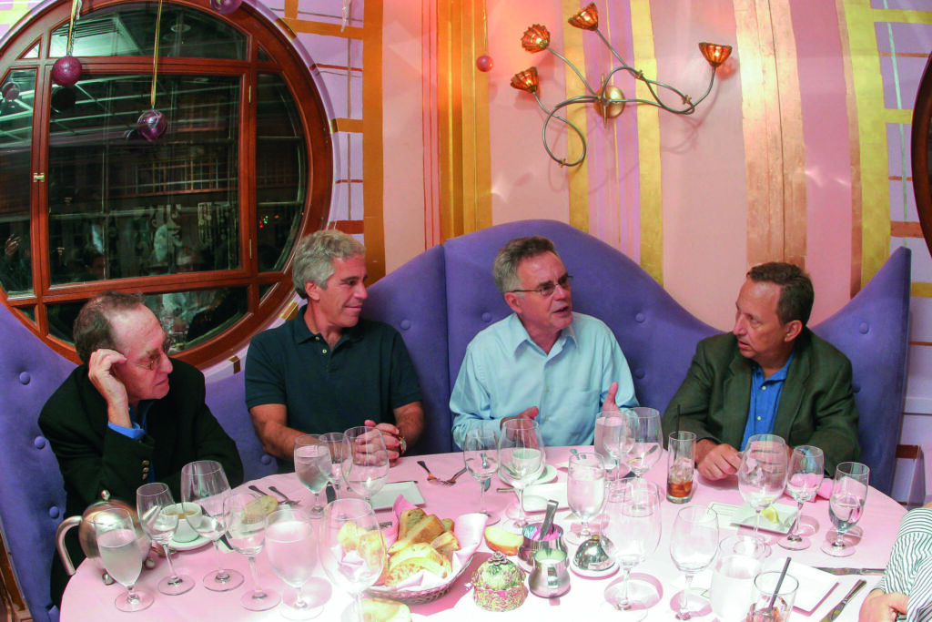 Epstein sits at a restaurant table with three other men, during a dinner he hosted at Harvard in 2004