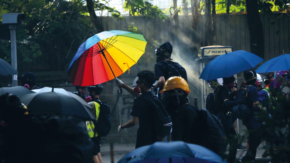 A protester uses an umbrella as a makeshift shield in front of a police station. Hong Kong, October 2019