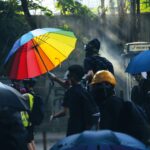 A protester uses an umbrella as a makeshift shield in front of a police station. Hong Kong, October 2019