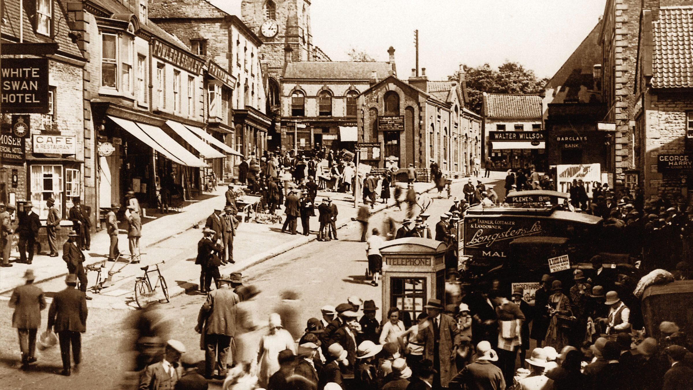 A sepia image of people walking through Pickering market place in Yorkshire, 1930s