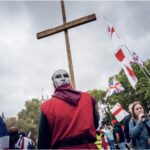 A man holds a cross at Tommy Robinson’s Unite the Kingdom rally in central London, May 2026