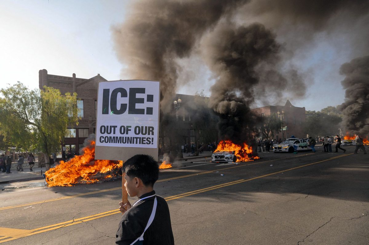 A boy holds up a sign reading "ICE: Out of our communities!" during a demonstration in LA