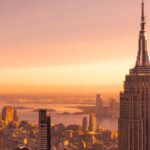 The New York City skyline against an orange sky