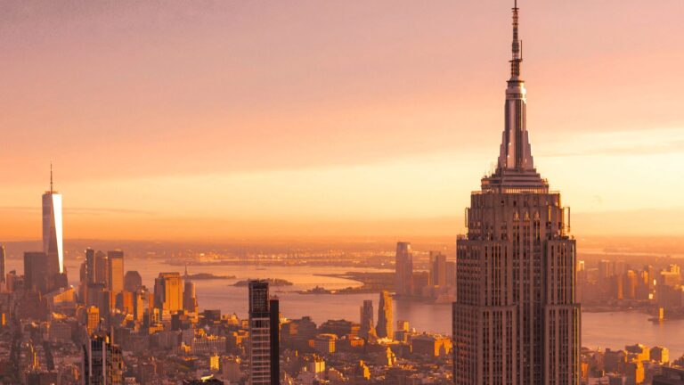 The New York City skyline against an orange sky