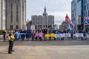 People hold up signs reading "Protect our women" and "Locals before illegals" at an anti-immigration protest in Aberdeen