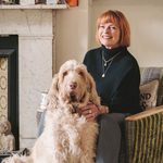 A photo of Janet Ellis sitting on a sofa with her dog