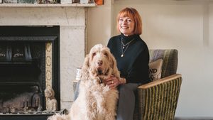 A photo of Janet Ellis sitting on a sofa with her dog