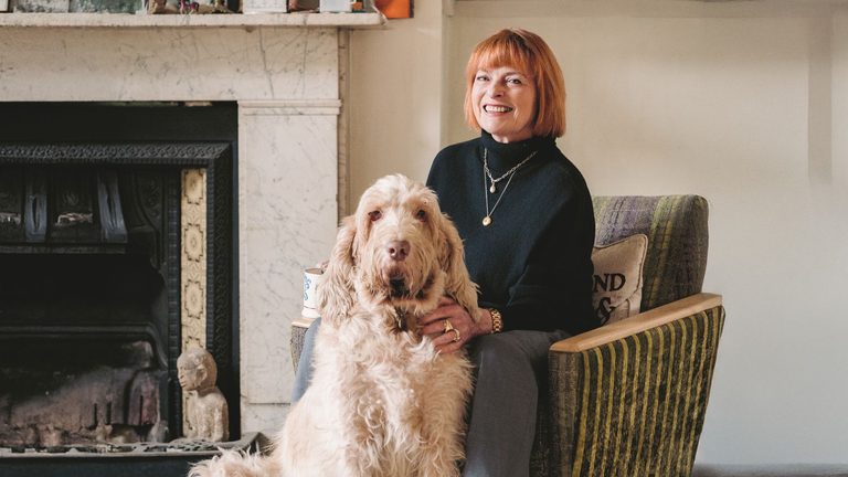 A photo of Janet Ellis sitting on a sofa with her dog