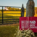 A sign propped up against a fence reads "No Data Center"