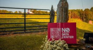 A sign propped up against a fence reads "No Data Center"