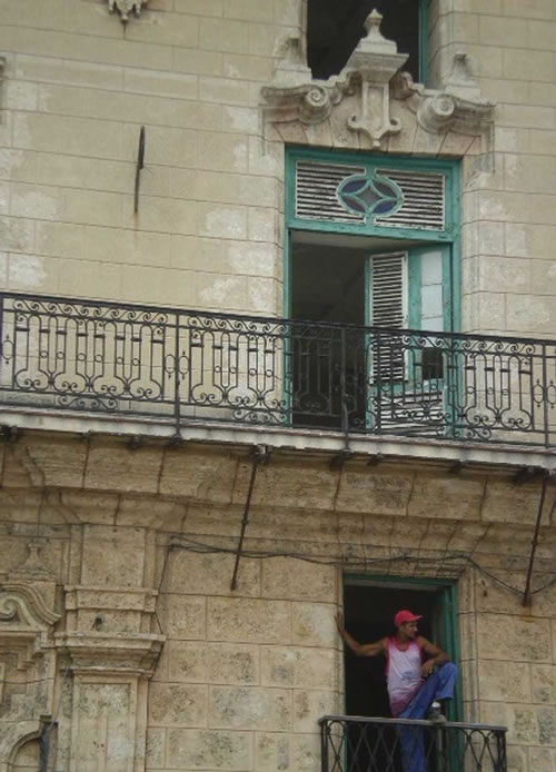 A man stands on the balcony of an old building in Havana