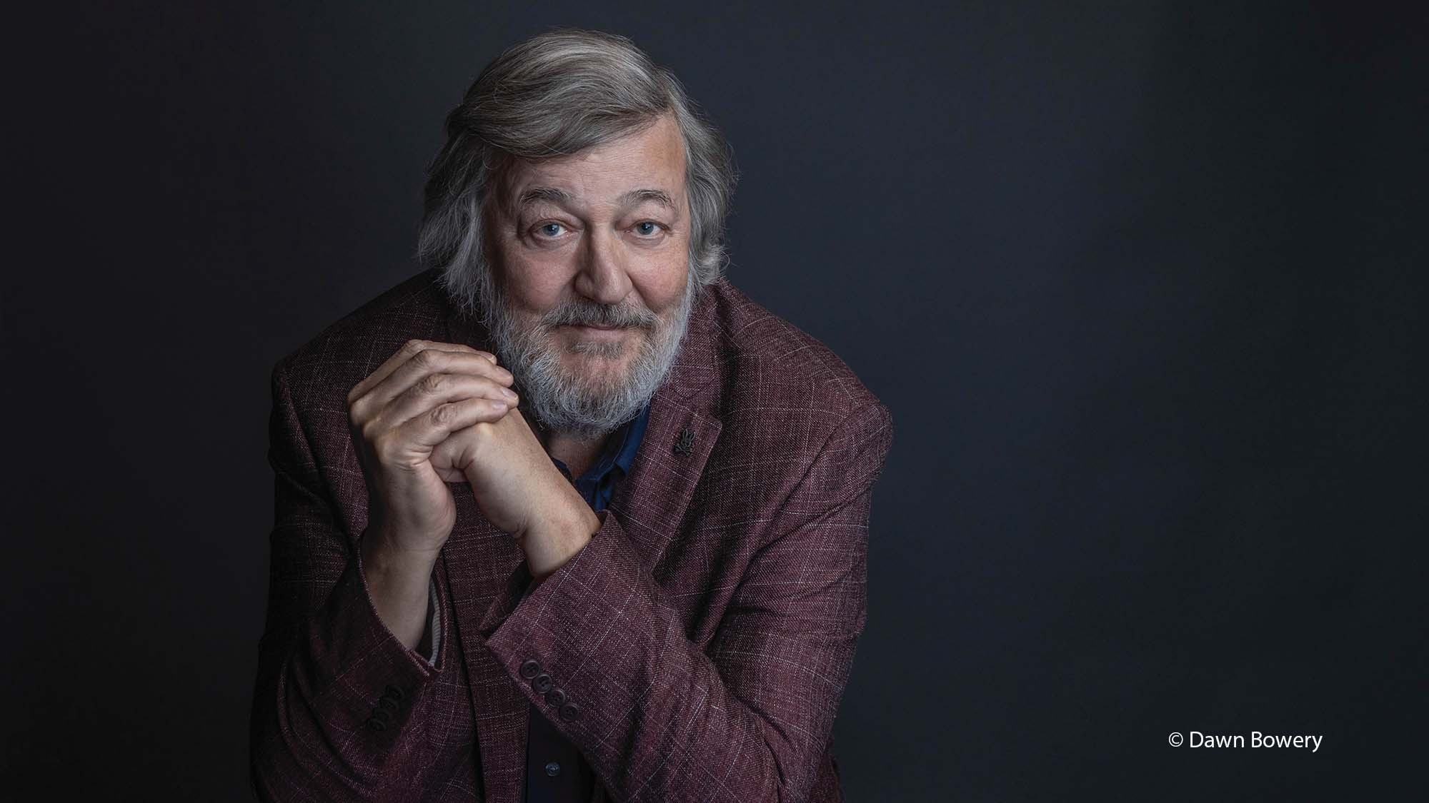 Stephen Fry wearing a maroon suit