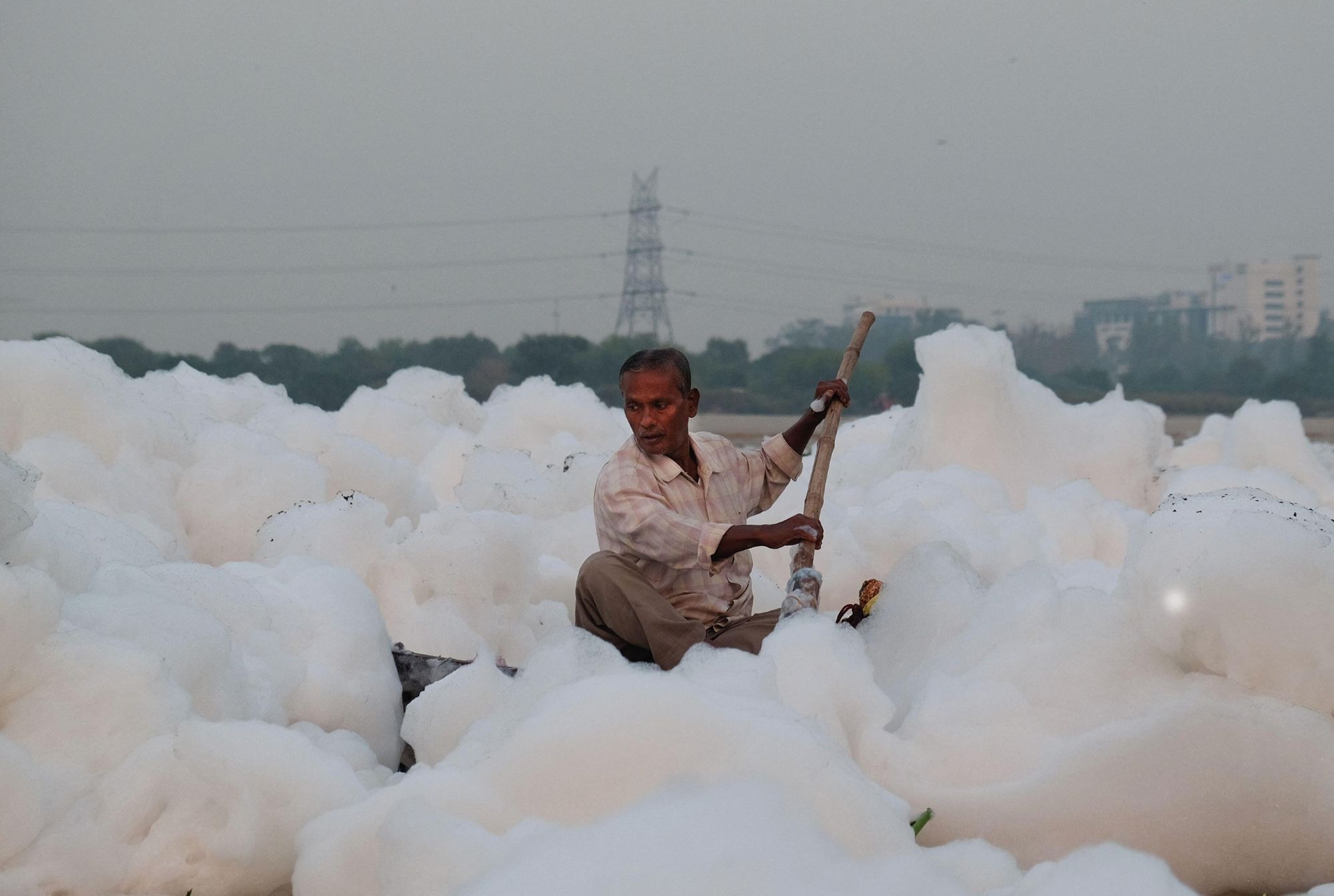 A man paddles through toxic foam on the Yamuna River in New Delhi