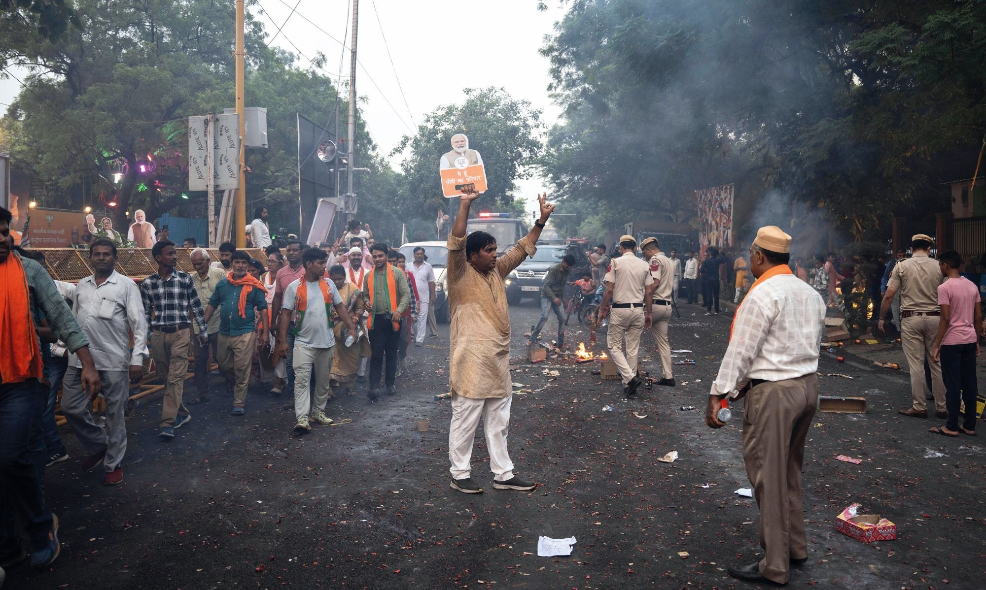 Supporters of Indian Prime Minister Narendra Modi celebrate in the street after he won a third consecutive term in June. In the centre, one man holds up a paper cutout of Modi in one hand while flashing the V for Victory sign with the other hand