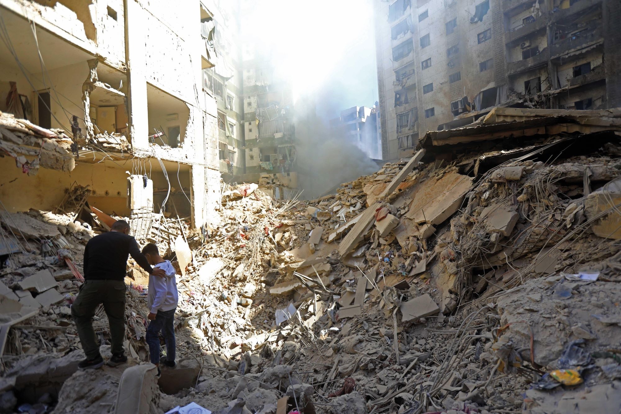 A man comforts a boy as they survey the ruins of an apartment block in Beirut that was destroyed by an Israeli strike