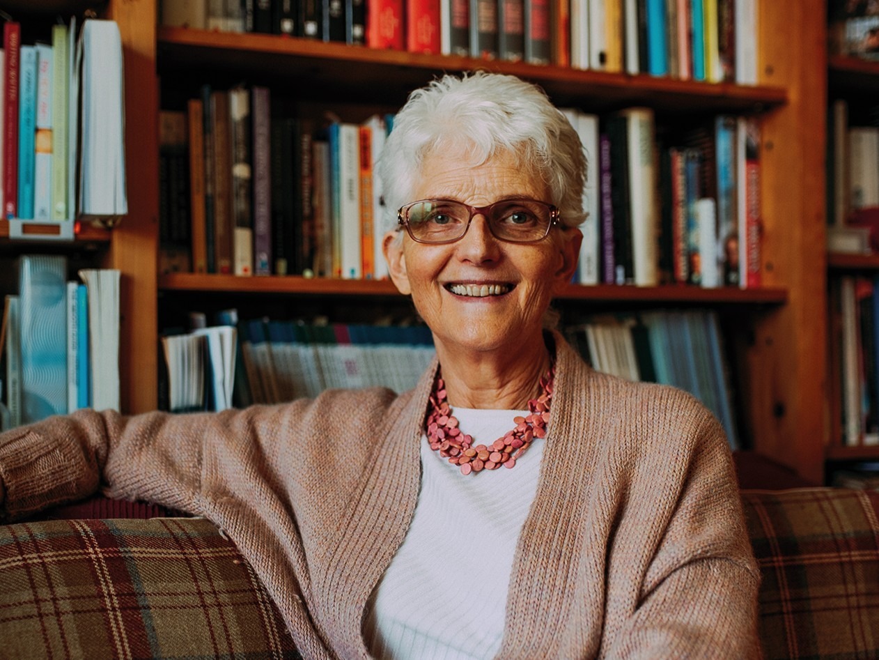 Therapist Gillie Jenkinson sits on a sofa in front of a bookcase