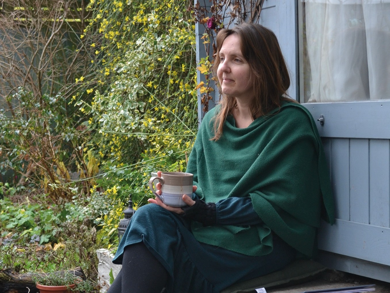Joy Brooks sits in her garden with a cup of tea