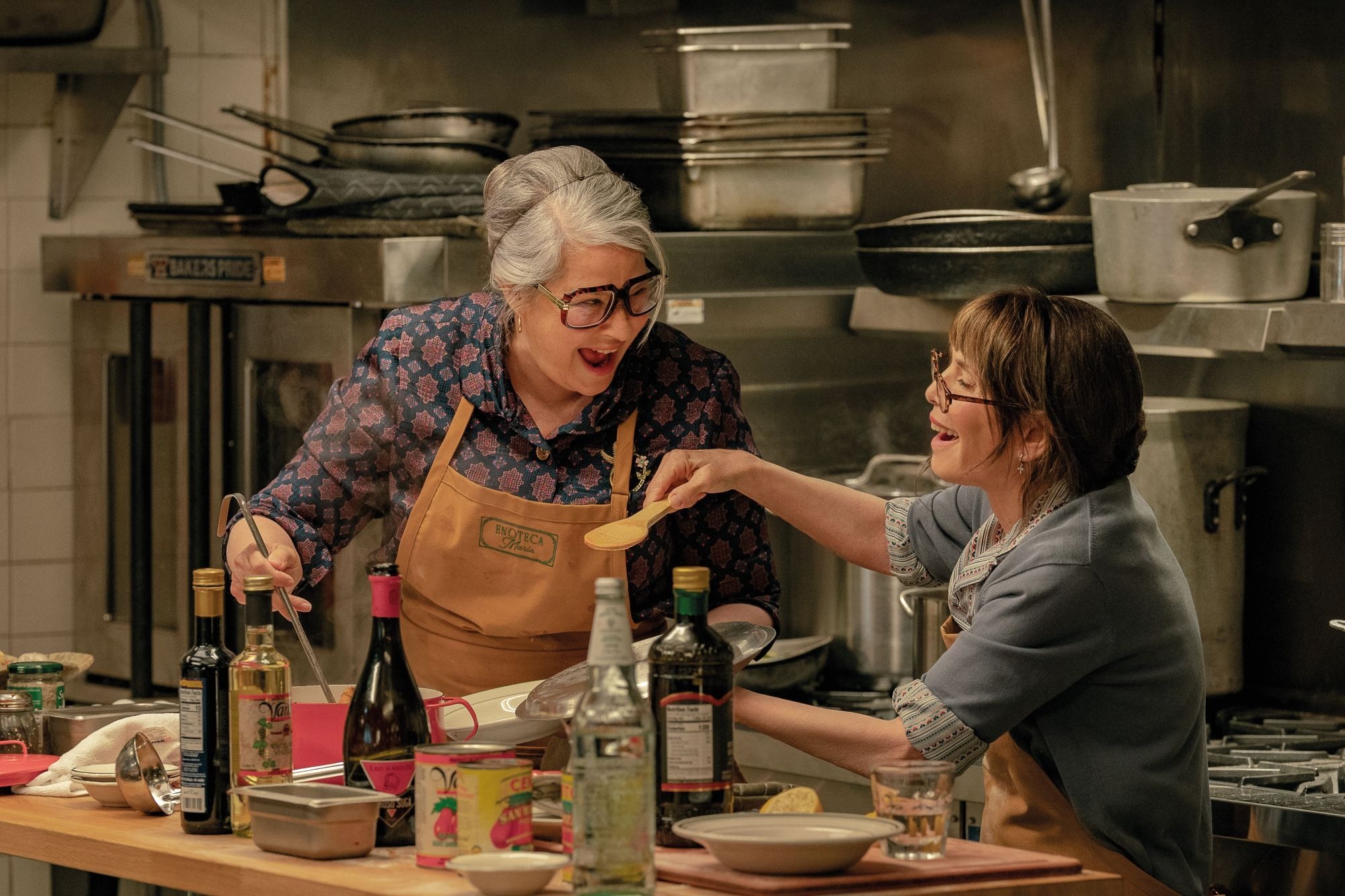 In a scene from 'Nonnas', two characters - Roberta and Teresa - laugh together as they cook