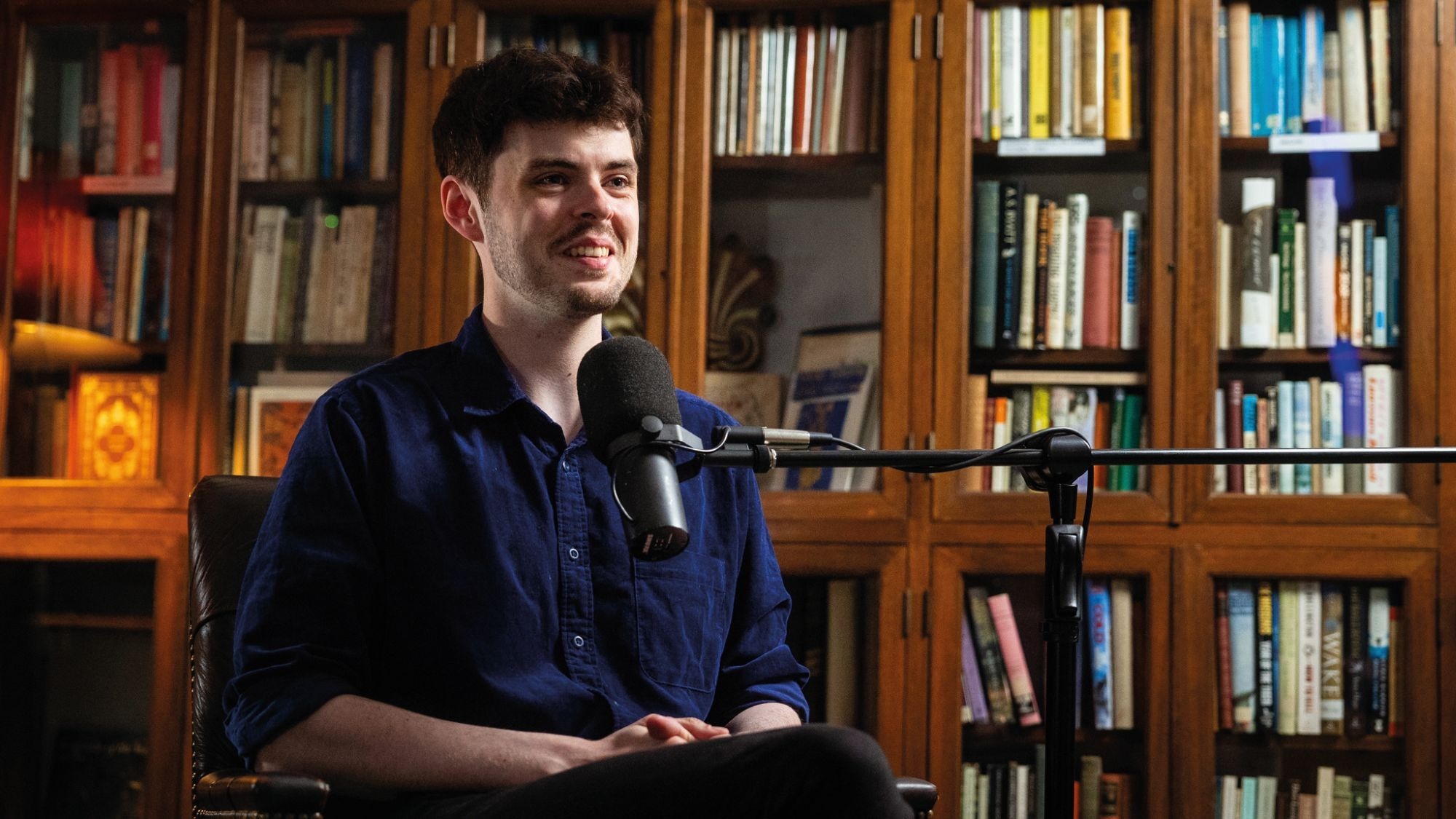 A photo of Alex O'Connor recording a podcast in a room lined with books