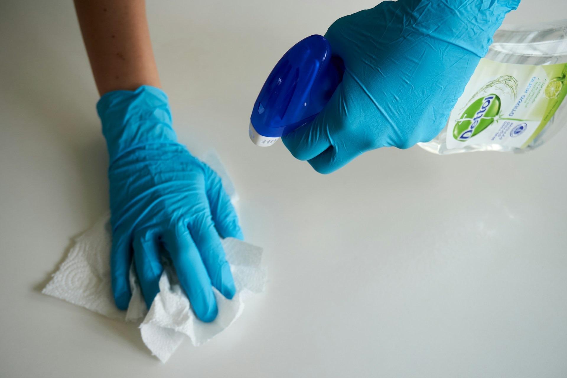 Somebody cleans a surface using antibacterial spray