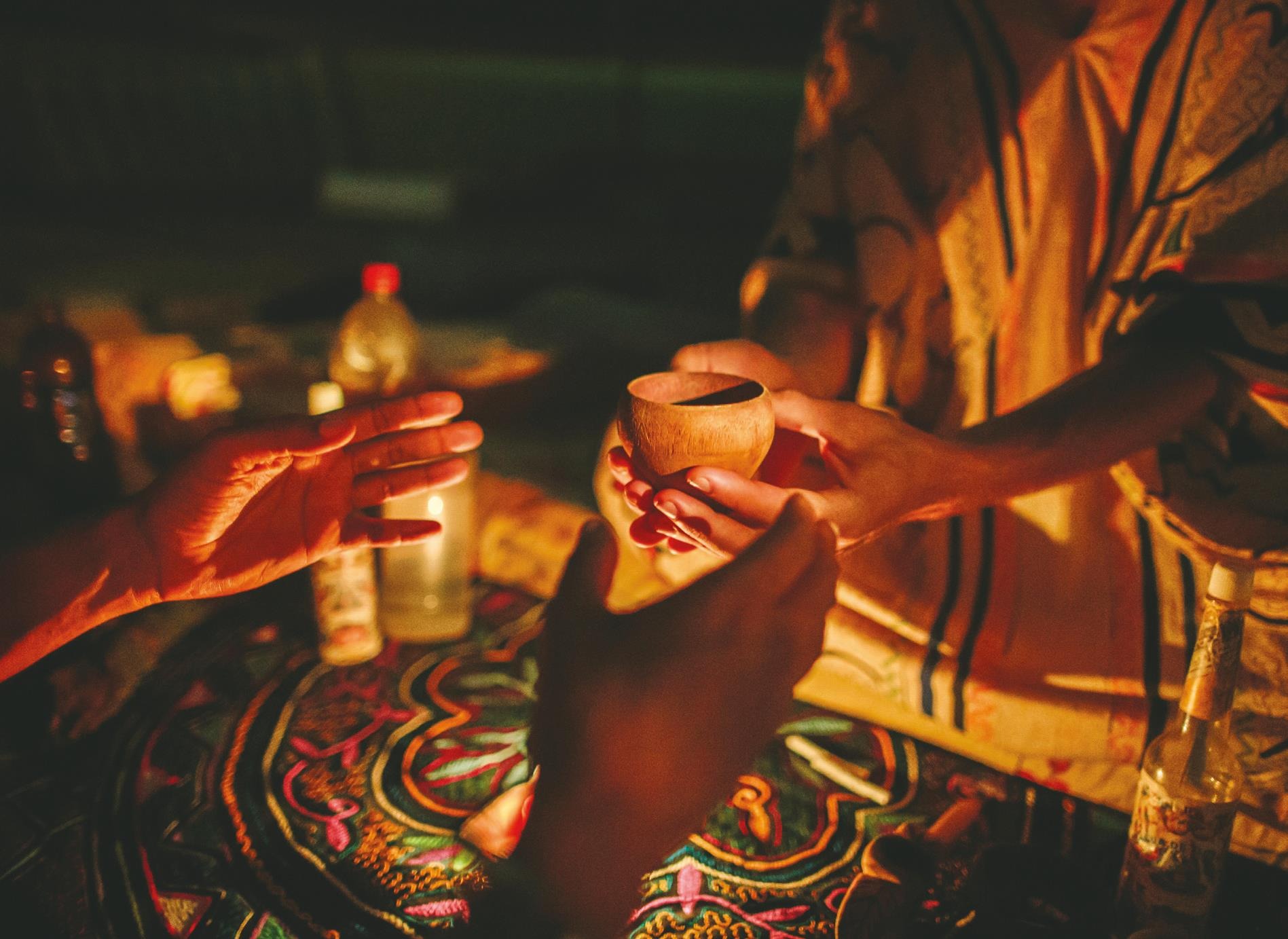 A man receives a cup of ayahuasca from a shaman in the Amazon jungle