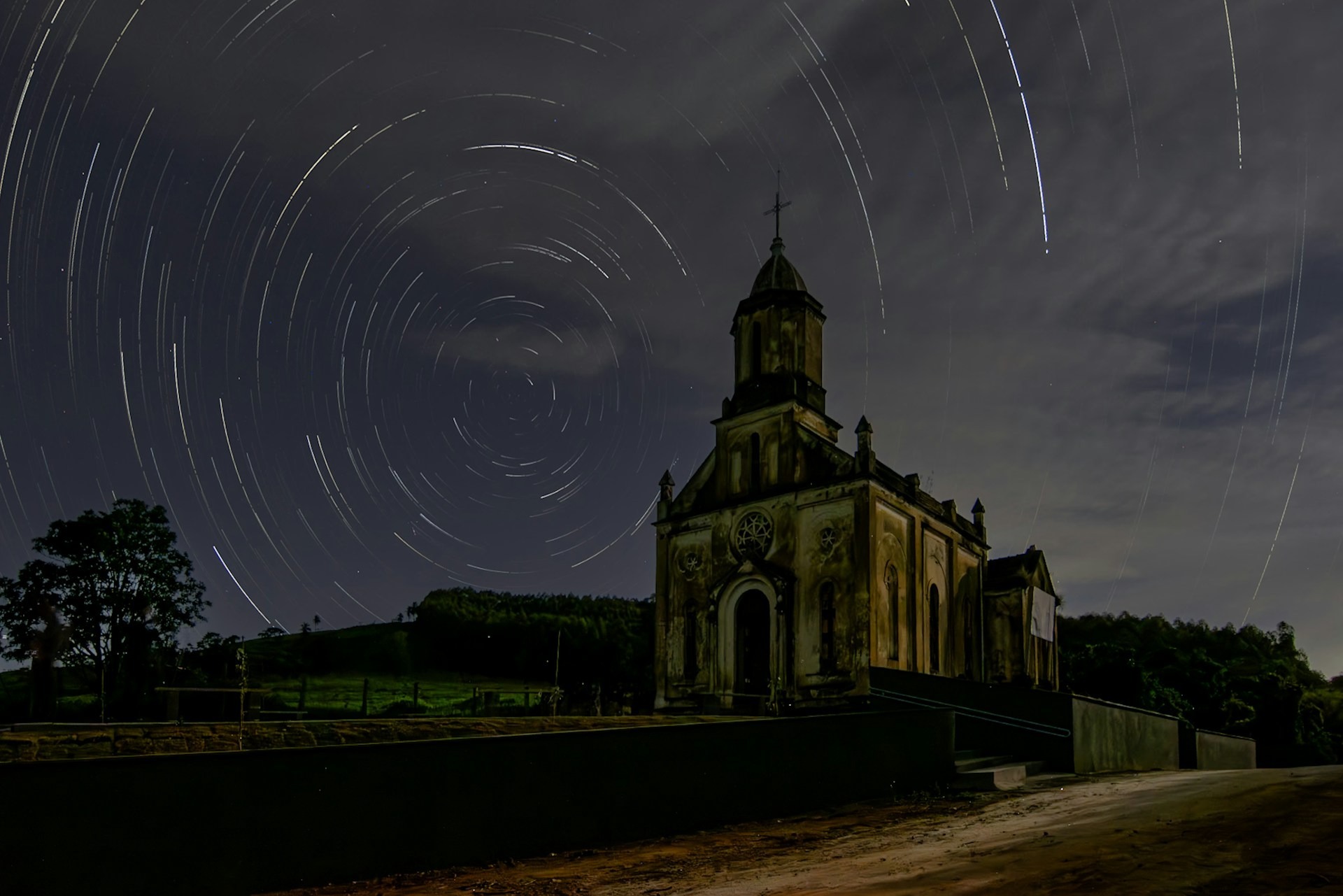 A church photographed at night with star trails in the background