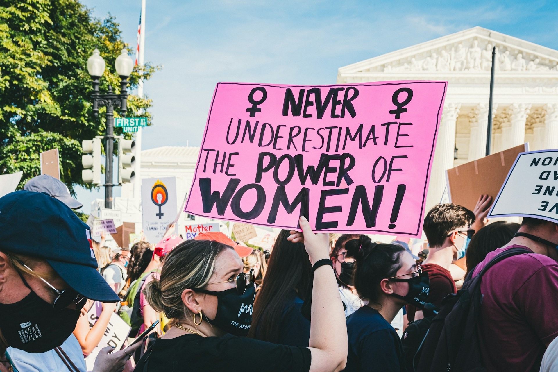 In the middle of a protest in Washington DC, a woman holds a sign reading 'Never underestimate the power of women'