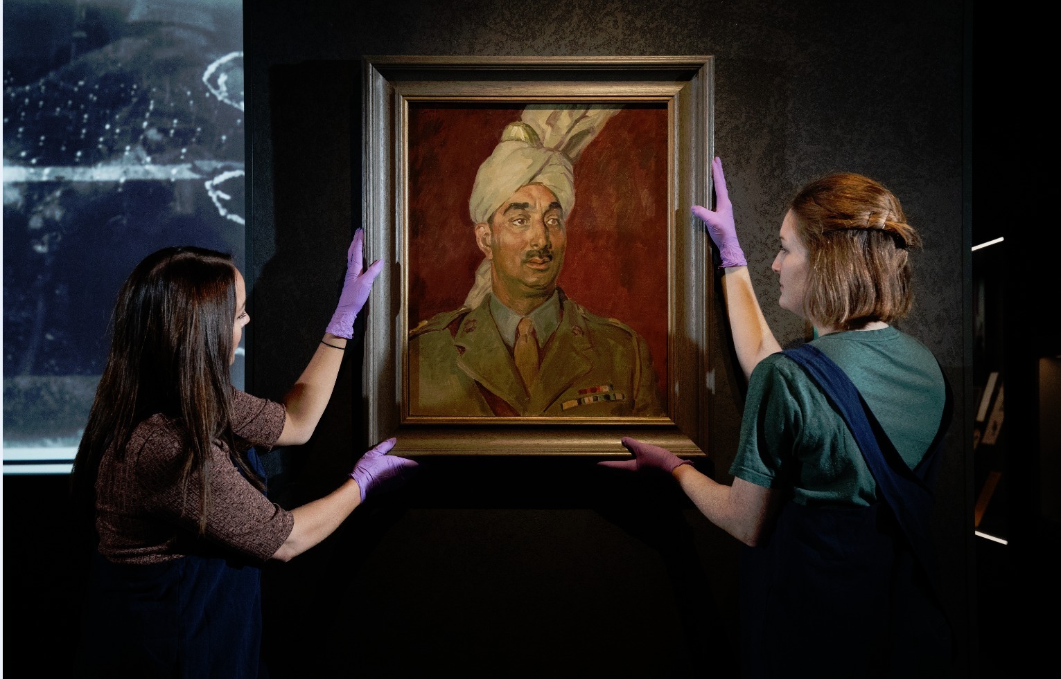 Hanging a portrait of Major Mahomed Akbar Khan at IWM London