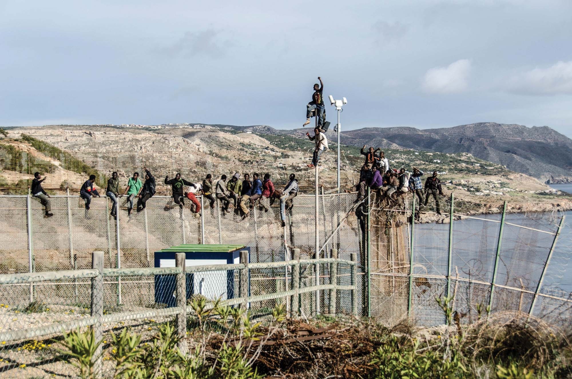 People scale border fences at one of Spain’s territorial enclaves in North Africa