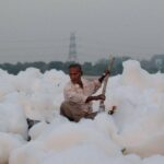 A man paddles through toxic foam on the Yamuna River in New Delhi