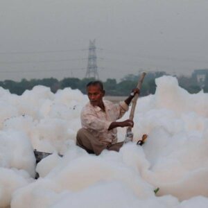 A man paddles through toxic foam on the Yamuna River in New Delhi